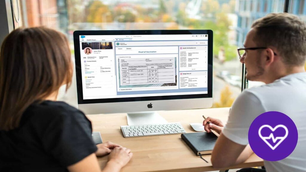 Two people sitting at a desk using Salesforce Health Cloud