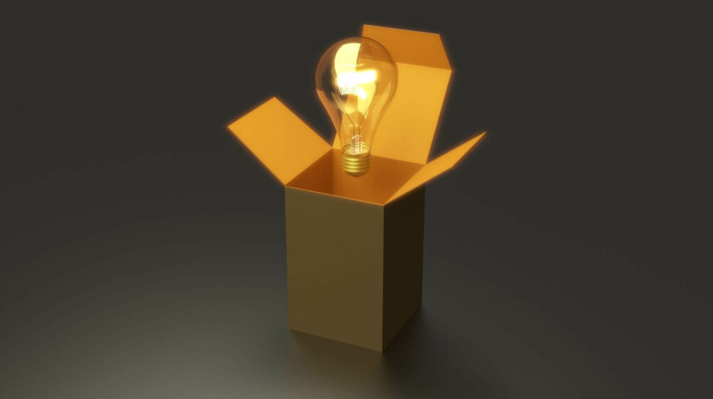 light bulb hovering over an open box located on a dark background 