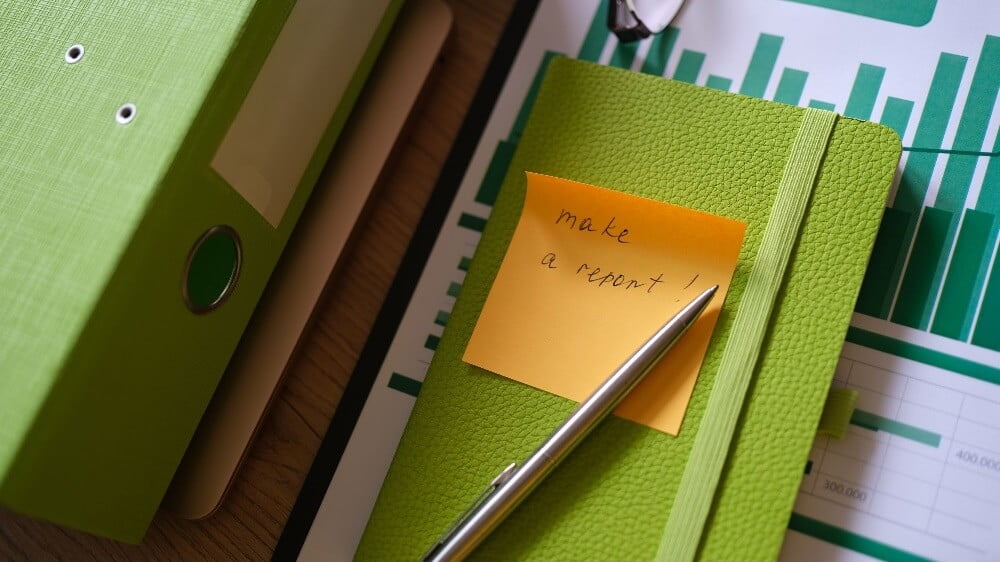 a notebook with a sticky note saying "make a report"
